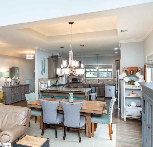 dining space with a raised ceiling, dark hardwood / wood-style flooring, ornamental molding, and sink