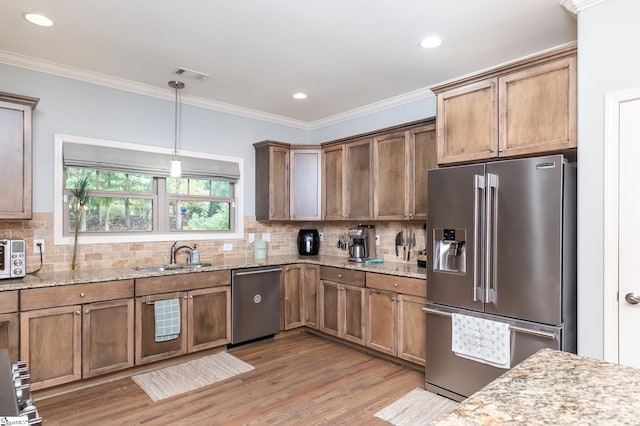 kitchen with sink, appliances with stainless steel finishes, tasteful backsplash, light hardwood / wood-style floors, and light stone counters