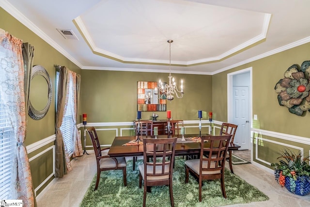 dining space with light carpet, an inviting chandelier, a raised ceiling, and ornamental molding