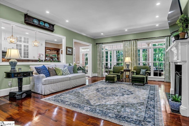 living room with crown molding, dark wood-type flooring, and an inviting chandelier