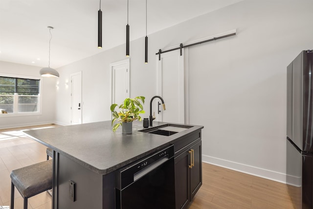 kitchen featuring dishwasher, a center island with sink, sink, stainless steel fridge, and a barn door