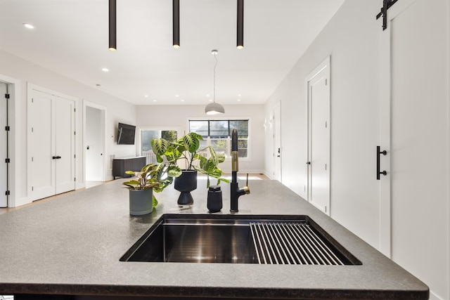 kitchen with a barn door, sink, and hanging light fixtures