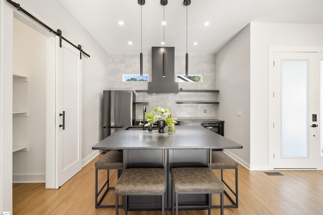 kitchen featuring a breakfast bar area, a barn door, sink, and hanging light fixtures