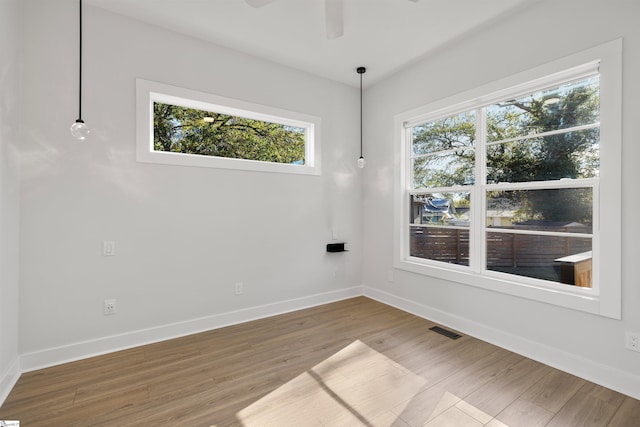 unfurnished room featuring hardwood / wood-style floors, ceiling fan, and a wealth of natural light