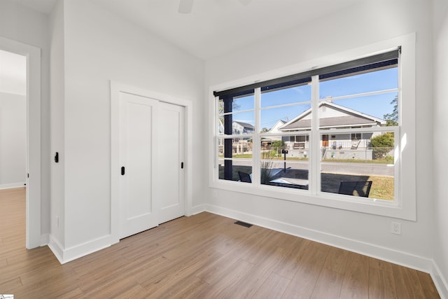 unfurnished bedroom featuring ceiling fan, light hardwood / wood-style floors, and a closet