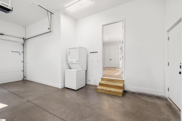 garage with a garage door opener and stacked washer / drying machine