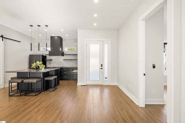 kitchen with a barn door, stainless steel fridge, a kitchen bar, a kitchen island, and custom exhaust hood