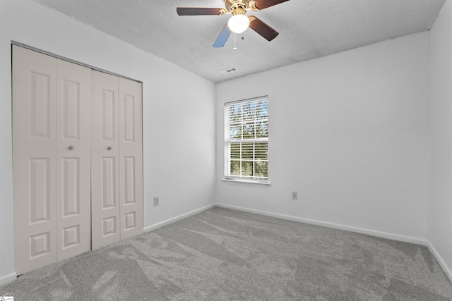 unfurnished bedroom featuring ceiling fan, a closet, light carpet, and a textured ceiling