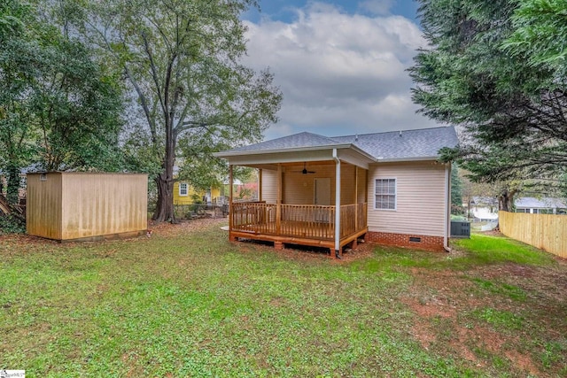 rear view of house with a storage shed, a wooden deck, cooling unit, ceiling fan, and a lawn