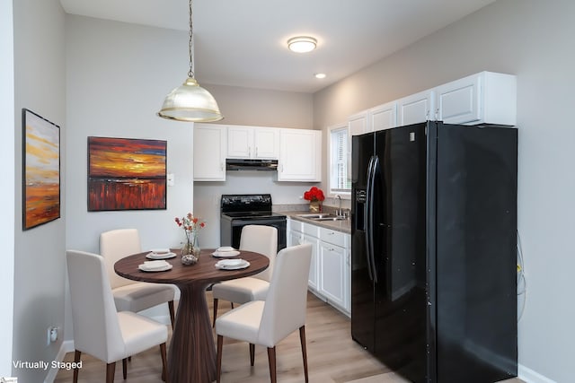 kitchen featuring white cabinetry, sink, pendant lighting, light hardwood / wood-style floors, and black appliances