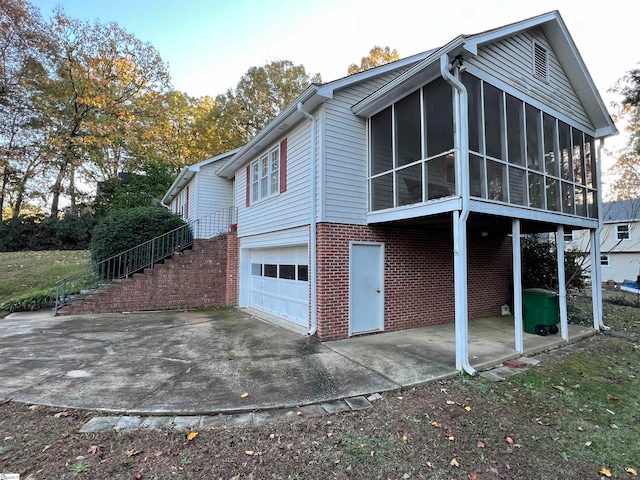 view of side of property with a garage, a patio area, and a sunroom