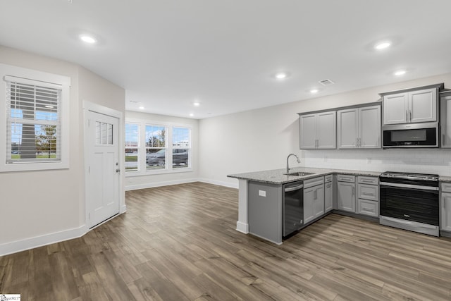 kitchen with sink, dark hardwood / wood-style flooring, kitchen peninsula, gray cabinets, and appliances with stainless steel finishes