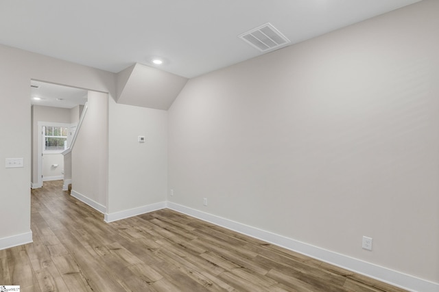 unfurnished room with light wood-type flooring and lofted ceiling