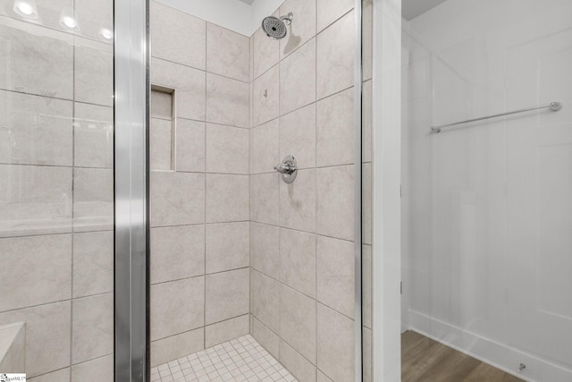 bathroom with a shower with shower door and wood-type flooring