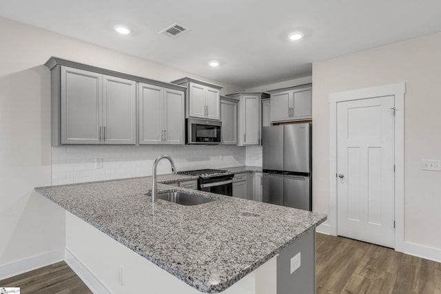 kitchen featuring sink, dark hardwood / wood-style floors, tasteful backsplash, kitchen peninsula, and stainless steel appliances