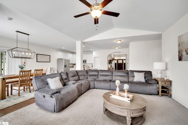 living room featuring light hardwood / wood-style flooring, ceiling fan with notable chandelier, and lofted ceiling