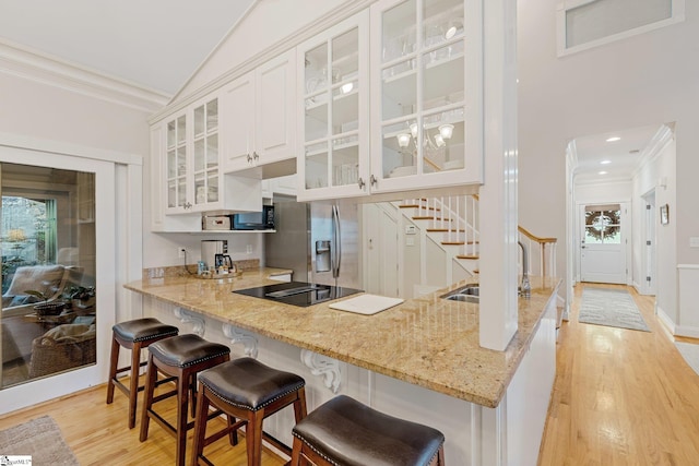 kitchen featuring light stone countertops, white cabinetry, light hardwood / wood-style flooring, and black appliances