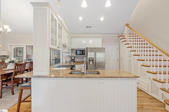 kitchen featuring sink, crown molding, decorative light fixtures, black appliances, and light wood-type flooring