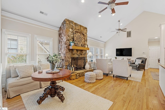 living room with high vaulted ceiling, ceiling fan, ornamental molding, a fireplace, and light hardwood / wood-style floors