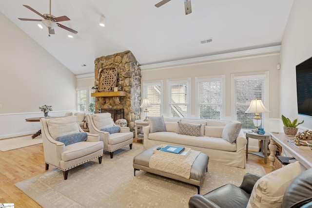 living room with ceiling fan, light wood-type flooring, a fireplace, and high vaulted ceiling