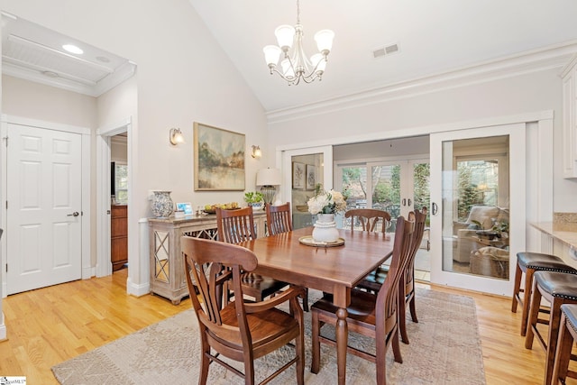 dining room featuring an inviting chandelier, high vaulted ceiling, light hardwood / wood-style flooring, and ornamental molding