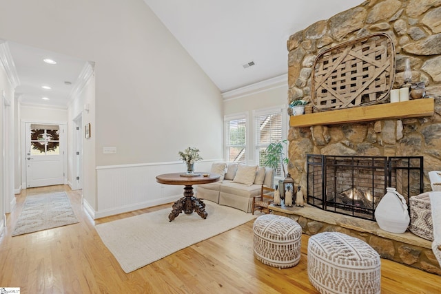 living room with a fireplace, hardwood / wood-style floors, high vaulted ceiling, and crown molding