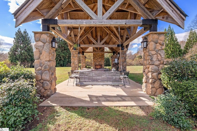 view of patio / terrace featuring an outdoor stone fireplace and a gazebo