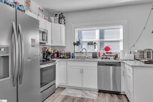 kitchen featuring sink, white cabinetry, stainless steel appliances, and light hardwood / wood-style flooring