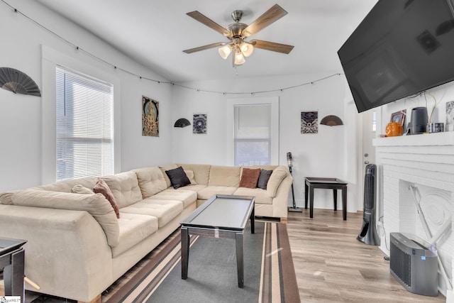 living room with a fireplace, light hardwood / wood-style flooring, and ceiling fan