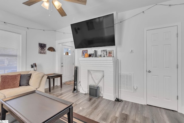 living room featuring hardwood / wood-style floors, ceiling fan, and a fireplace