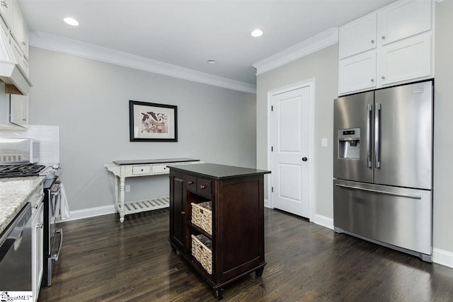 kitchen featuring white cabinetry, dark wood-type flooring, appliances with stainless steel finishes, a kitchen island, and ornamental molding