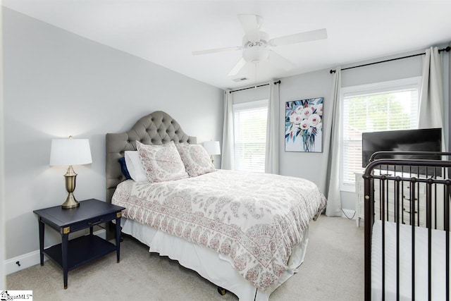 bedroom featuring ceiling fan, light carpet, and multiple windows