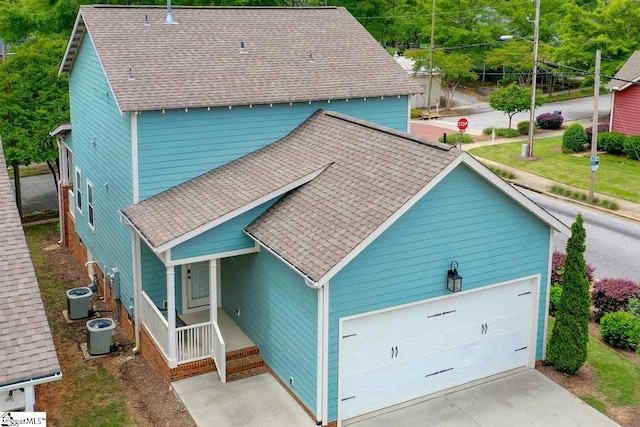 view of front of home with covered porch, a garage, and central air condition unit