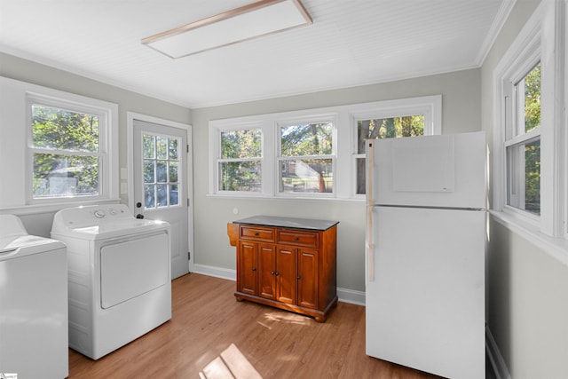 laundry area with a healthy amount of sunlight, light wood-type flooring, ornamental molding, and independent washer and dryer