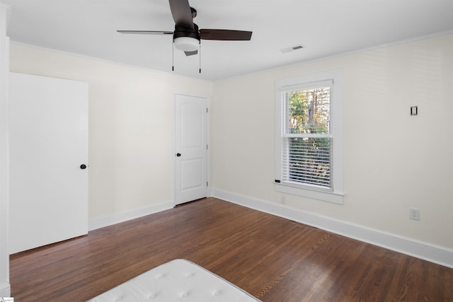 spare room featuring crown molding, ceiling fan, and dark wood-type flooring