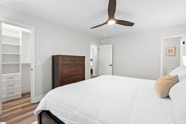 bedroom with connected bathroom, a spacious closet, light hardwood / wood-style flooring, and ceiling fan