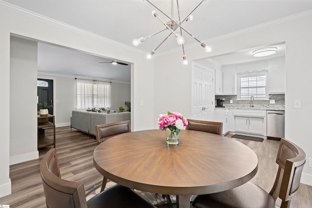 dining space featuring crown molding, light hardwood / wood-style flooring, a healthy amount of sunlight, and ceiling fan with notable chandelier