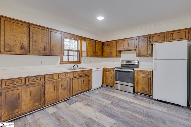 kitchen with ornamental molding, white appliances, sink, and light hardwood / wood-style flooring