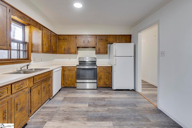 kitchen featuring crown molding, sink, white appliances, and light hardwood / wood-style flooring