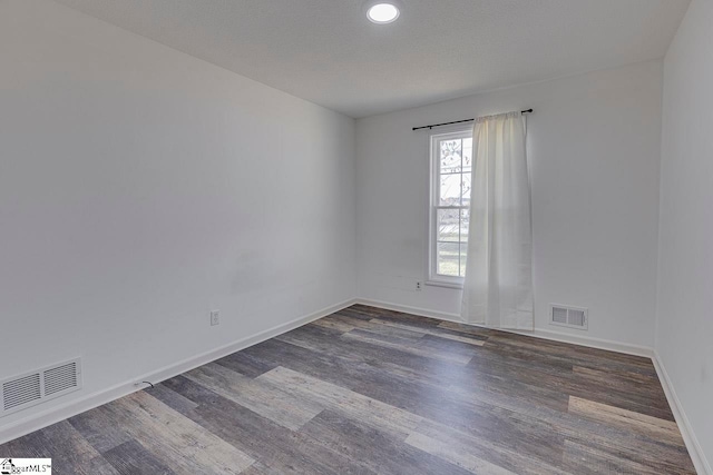 spare room with a textured ceiling and dark wood-type flooring