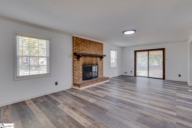 unfurnished living room featuring a fireplace, hardwood / wood-style floors, plenty of natural light, and crown molding