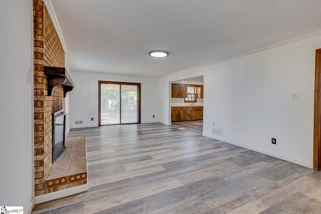 unfurnished living room featuring a fireplace, ornamental molding, a textured ceiling, and hardwood / wood-style flooring