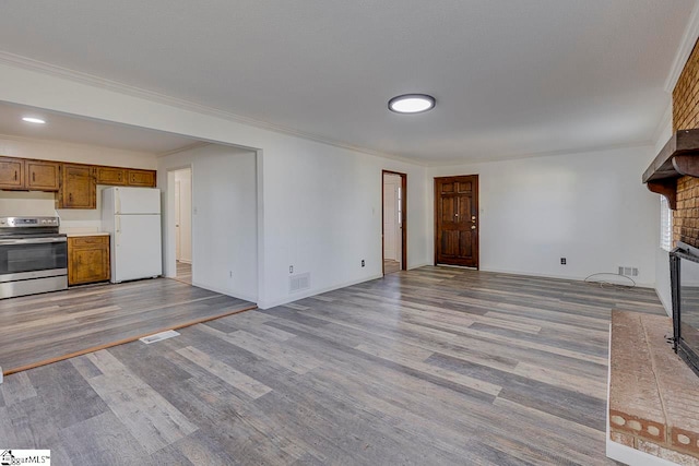 unfurnished living room with a fireplace, ornamental molding, and light hardwood / wood-style flooring