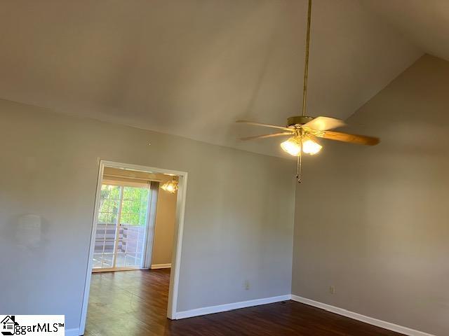 empty room with ceiling fan, dark wood-type flooring, and vaulted ceiling