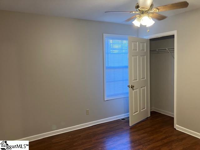 unfurnished bedroom with ceiling fan, dark hardwood / wood-style floors, and a closet