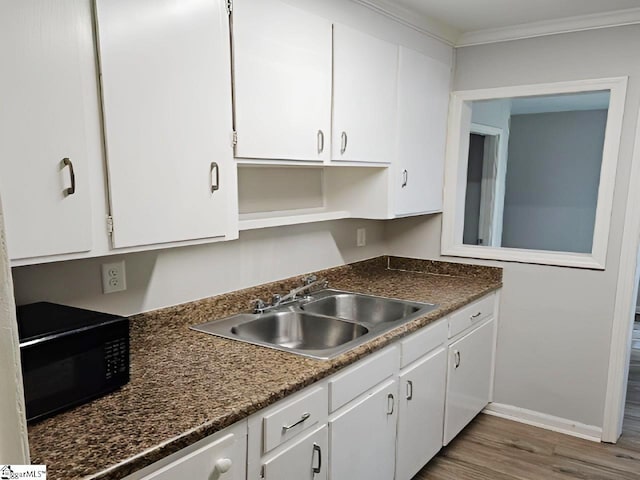 kitchen featuring white cabinets, crown molding, dark wood-type flooring, and sink