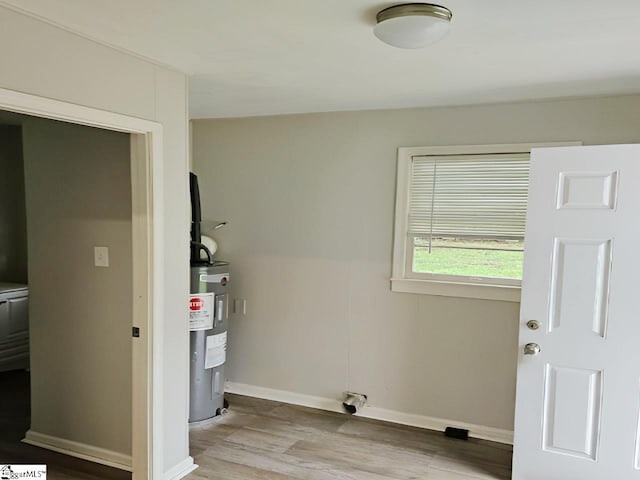 clothes washing area featuring electric water heater and light hardwood / wood-style flooring