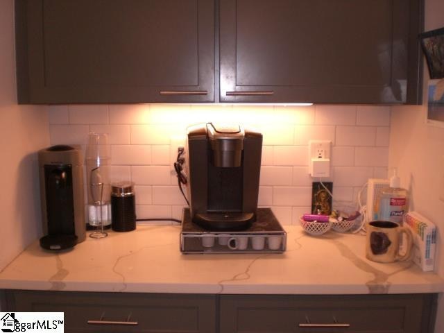 kitchen featuring decorative backsplash, dark brown cabinets, and light stone counters