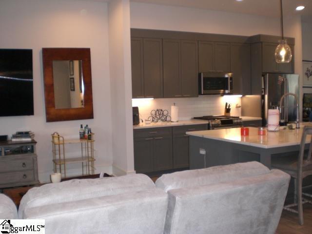 kitchen with a breakfast bar, dark wood-type flooring, hanging light fixtures, appliances with stainless steel finishes, and a kitchen island