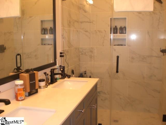 bathroom with vanity, an enclosed shower, and tile walls